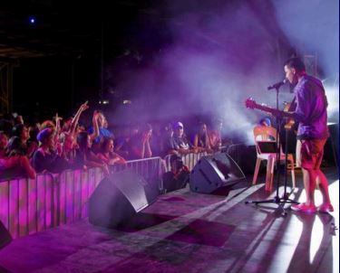 A musician performing in the stage in front of a crowd.